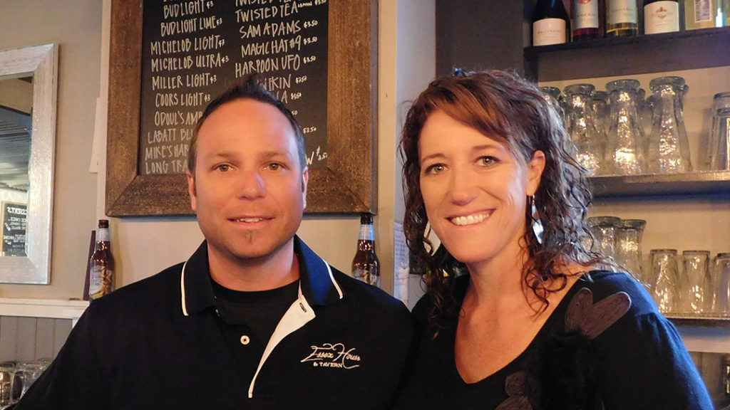 Dave and Melinda Gervais-Lamoureux where t-shirts with the Essex House logo and smile under the sign in the bar