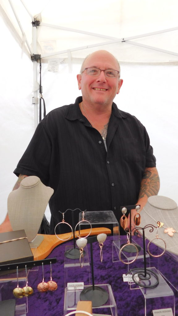Dave Kaczynski of Khaos Designs in Hardwick stands in front of a farmers market display of his handmade jewelry